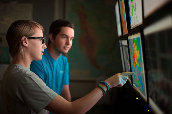Two climate science students study a computer monitor